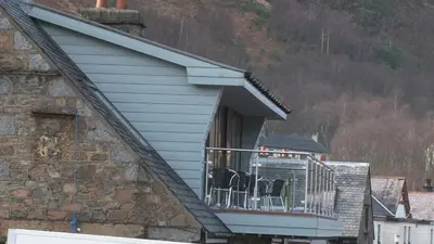 a house with a balcony with chairs on it at Highland Getaway in Kinlochleven