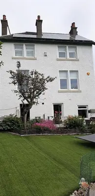 a white house with a tree in front of a yard at Glasgow Emo in Glasgow