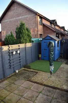 a garden with a blue shed and a fence at Kelpies Serviced Apartments Hamilton- 2 Bedrooms in Falkirk