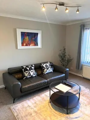 a living room with a leather couch and a table at Kelpies Serviced Apartments Hamilton- 2 Bedrooms in Falkirk