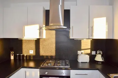 a kitchen with white cabinets and a stove top oven at Kelpies Serviced Apartments Hamilton- 2 Bedrooms in Falkirk