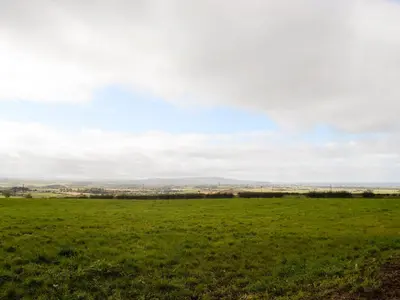 a field of green grass with a city in the distance at Torcross Barn in Tarbolton