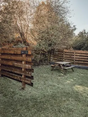 a wooden fence and a picnic table in the grass at Strathyre Camping Pods in Strathyre