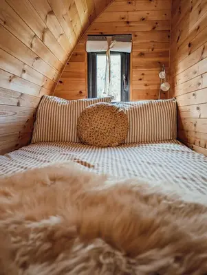 a bed in a room with wooden walls at Strathyre Camping Pods in Strathyre