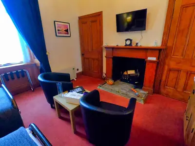 a living room with a fireplace with chairs and a table at Gowanlea Heights in Campbeltown