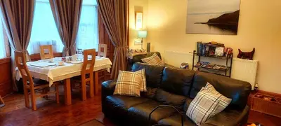 a living room with a black leather couch and a table at Gowanlea Heights in Campbeltown