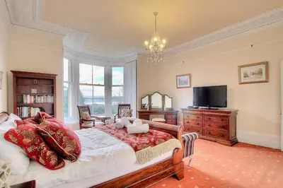 a bedroom with a large bed and a tv at Duneira House in Helensburgh