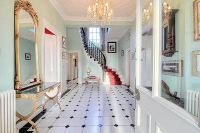 a hallway with a staircase and a chandelier at Duneira House in Helensburgh