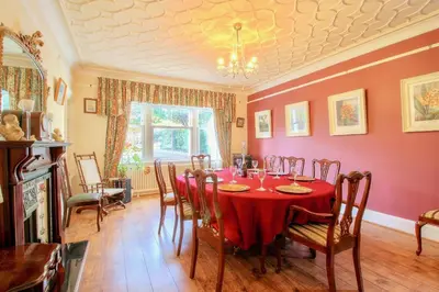 a dining room with a red table and chairs at Duneira House in Helensburgh