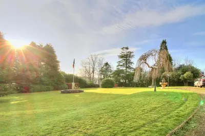 a grassy field with the sun shining in a park at Duneira House in Helensburgh