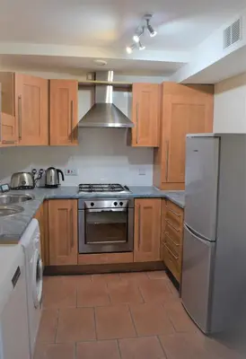 a kitchen with wooden cabinets and stainless steel appliances at Airdrie Apartments in Airdrie