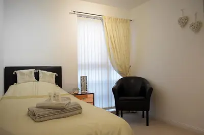 a bedroom with a bed and a black chair at Airdrie Apartments in Airdrie
