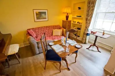 a living room with a bed and a table at Thistle Street Apartment at Heart of the City Centre in Edinburgh