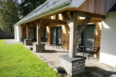a covered patio with chairs and tables on a house at The Loch Lomond Guesthouse in Balloch