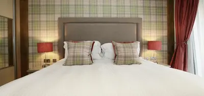 a white bed with two pillows and two lamps at The Loch Lomond Guesthouse in Balloch