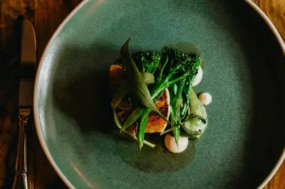 a green plate of food with vegetables on a table at Coorie Inn Restaurant and Rooms in Crieff