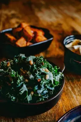 a black bowl of salad on a wooden table at Coorie Inn Restaurant and Rooms in Crieff