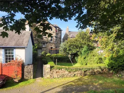 a house with a stone wall in front of a yard at Beach House No1 With Amazing Sea Views And Direct Beach Access in Fairlie
