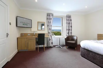 a hotel room with a bed and a desk and a window at Woodland Bay Hotel in Girvan
