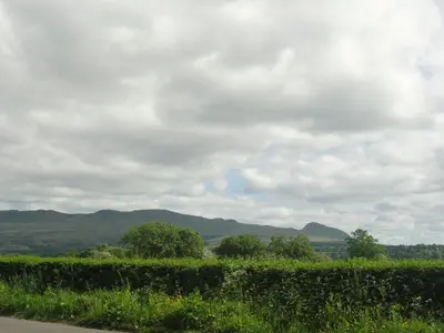 a view of a field with mountains in the background at Dunroamin Apartment in Drymen