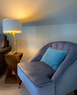 a couch with a blue pillow and a lamp at Dunroamin Apartment in Drymen
