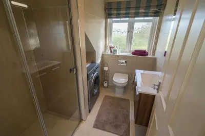 a bathroom with a shower and a toilet and a sink at Dunroamin Apartment in Drymen