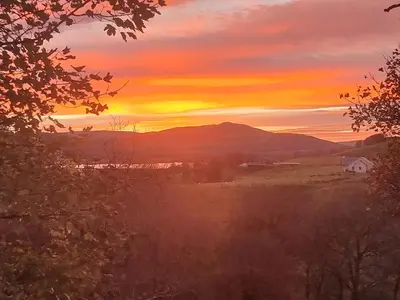 a sunset over a field with a house in the foreground at B&B Drum Farm in Stirling