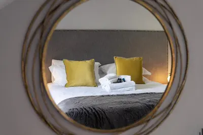 a reflection of a bed with yellow pillows in a mirror at Sweeney Motherwell in Motherwell