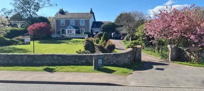 a house with a stone wall in front of a street at CREAG DHUBH COUNTRY HOUSE in Inveraray