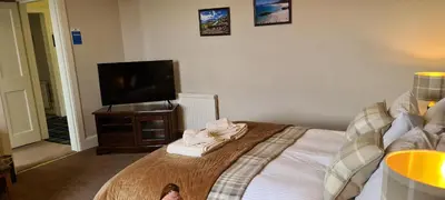 a bedroom with a bed and a flat screen tv at CREAG DHUBH COUNTRY HOUSE in Inveraray