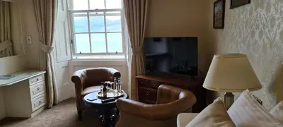 a hotel room with a bed and a table and a television at CREAG DHUBH COUNTRY HOUSE in Inveraray