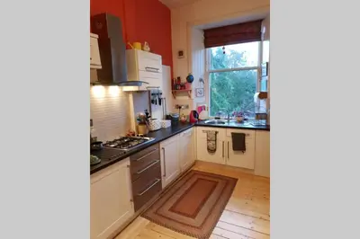 a kitchen with white cabinets and a large window at Woodburn Terrace, Morningside, Edinburgh in Edinburgh