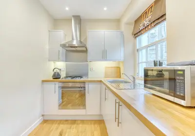 a kitchen with white cabinets and a large window at The Gloucester Lane Residence in Edinburgh