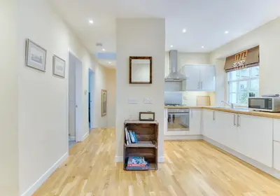 a kitchen with white cabinets and a wooden floor at The Gloucester Lane Residence in Edinburgh