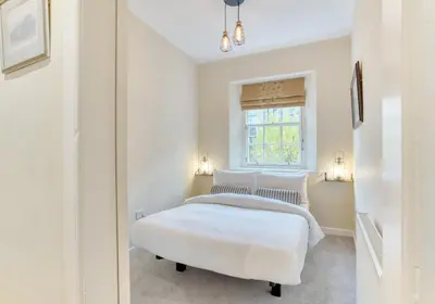 a white bedroom with two beds and a window at The Gloucester Lane Residence in Edinburgh
