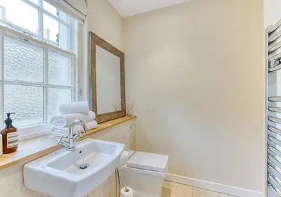 a bathroom with a sink and a toilet and a window at The Gloucester Lane Residence in Edinburgh