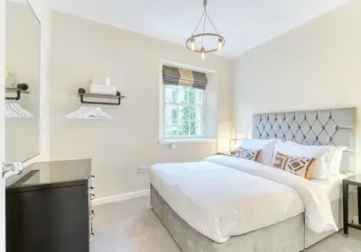 a white bedroom with a large bed and a window at The Gloucester Lane Residence in Edinburgh