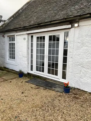 a white house with a sliding glass door at COACHMAN COTTAGE OUTSIDE HOT TUB in Beith