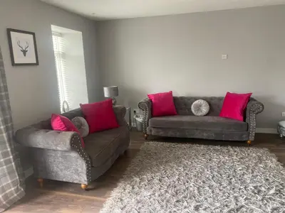 a living room with two couches and pink pillows at COACHMAN COTTAGE OUTSIDE HOT TUB in Beith