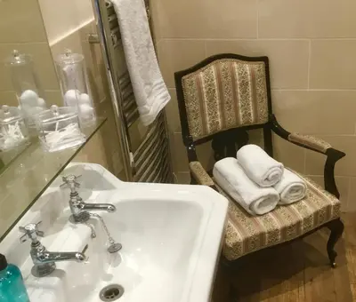 a bathroom with a sink and a chair with towels at Hunters Guest House in Brodick