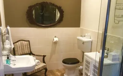 a bathroom with a toilet and a sink and a mirror at Hunters Guest House in Brodick