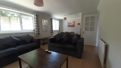 a living room with a black couch and a table at Carvetii - Clark House - Spacious ground floor flat in Rosyth