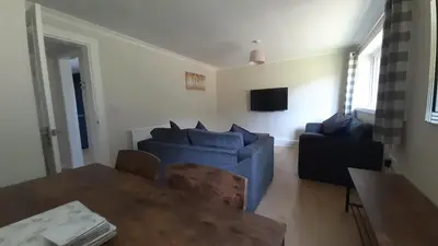 a living room with a blue couch and a table at Carvetii - Clark House - Spacious ground floor flat in Rosyth