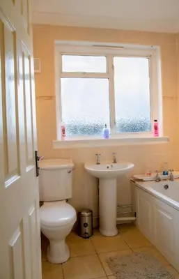 a bathroom with a toilet and a sink and a window at Carvetii - Derwent House - Spacious 2nd floor flat in Grangemouth