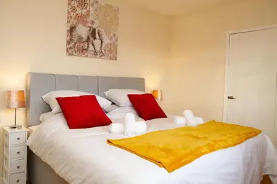 a bedroom with a large white bed with red pillows at Carvetii - Derwent House - Spacious 2nd floor flat in Grangemouth