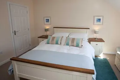 a bedroom with a white bed with two pillows on it at Killinallan Cottage in Port Charlotte