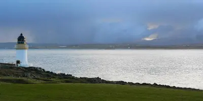 a lighthouse sitting on the edge of a body of water at Kilchoman in Port Charlotte