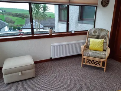 a chair and a ottoman in a room with a window at Leafield Holiday Home in Stranraer