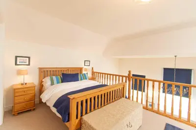 a bedroom with a bed and a wooden railing at Ardnave in Port Charlotte