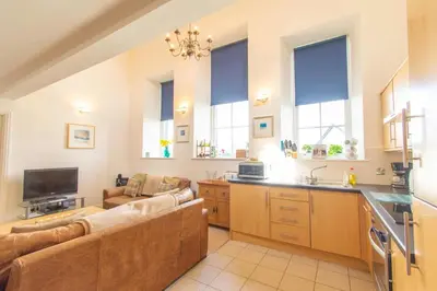 a large living room with a couch and a kitchen at Ardnave in Port Charlotte